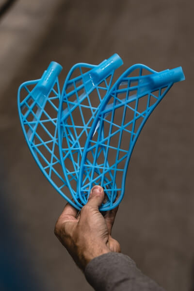 A hand holds three blue lattice-patterned plastic objects on the left; another hand holds packaged white grips labeled "GRIPS." on the right.